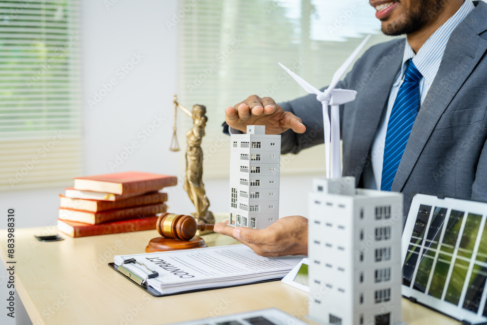 Φωτογραφία A male Asian lawyer in a formal suit works at his desk, focusing on contracts, legal matters, and urban planning issues such as building models, zoning, ordinances, and municipal regulations