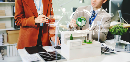 businesspeople standing neare table looking at model of building from residential project. Green business company and Solar Energy photo