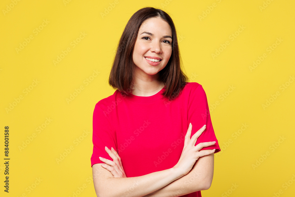 Young smiling happy confident cheerful woman she wear pink t-shirt casual clothes hold hands crossed folded look camera isolated on plain yellow orange background studio portrait. Lifestyle concept. Young smiling happy confident cheerful woman she wear pink t-shirt casual clothes hold hands crossed folded look camera isolated on plain yellow orange background studio portrait. Lifestyle concept.