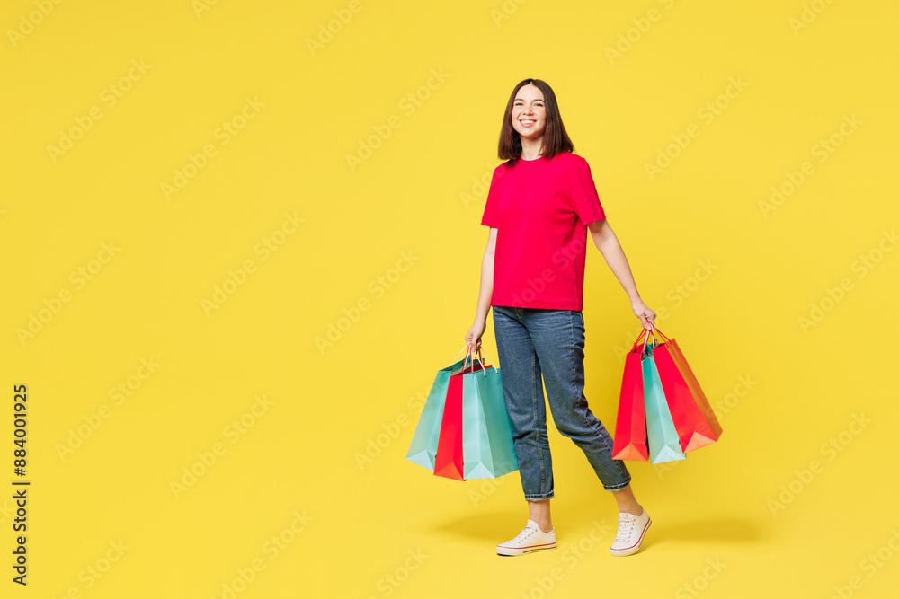 Full body young smiling happy shocked fun woman wears pink casual clothes hold in hand paper package bags after shopping walk go isolated on plain yellow background. Black Friday sale buy day concept. Full body young smiling happy shocked fun woman wears pink casual clothes hold in hand paper package bags after shopping walk go isolated on plain yellow background. Black Friday sale buy day concept.