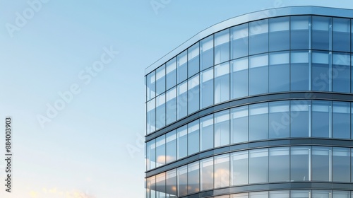 A tall, modern office building with a curved facade of glass reflecting the sky