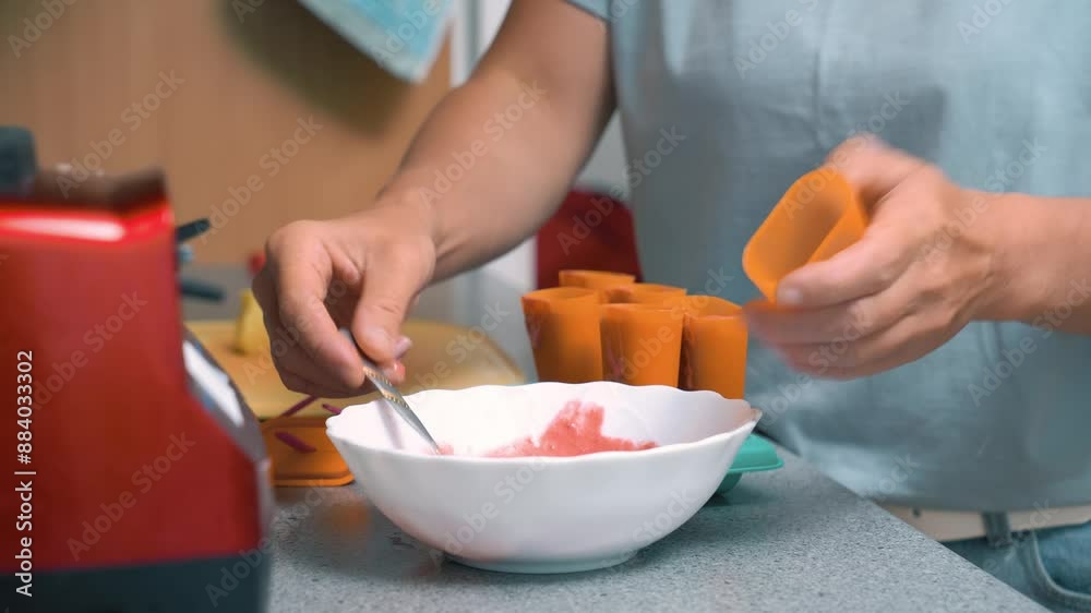 Making homemade popsicles, ice cream lollies, frozen juice. Women's hands hold an ice cream mold. Making homemade popsicles, ice cream lollies, frozen juice. Women's hands hold an ice cream mold.
