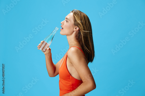 Obraz na plátně Refreshing hydration young woman in vibrant orange swimsuit quenching her thirst