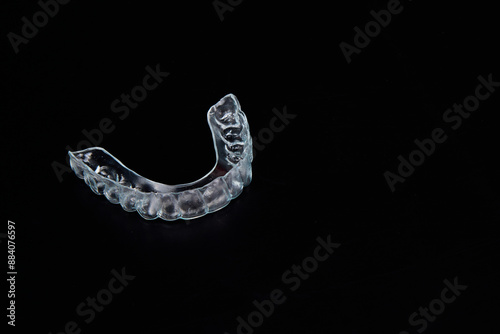 A clear mouth guard is placed on a black tabletop