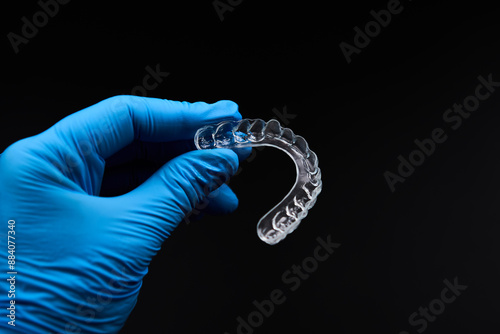 A person dressed in blue gloves holds a transparent mouthpiece