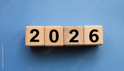 Wooden cubes with number 2026 on blue backdrop. New year. Wood blocks. Close-up. Flat lay.