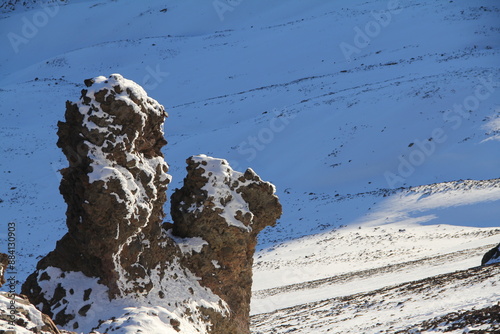 Sunlit rock formation on snow-covered volcano in Teide National Park, Tenerife, Canary Islands. The contrast between the warm-colored rock and the snowy mountainside creates a stunning visual display. photo