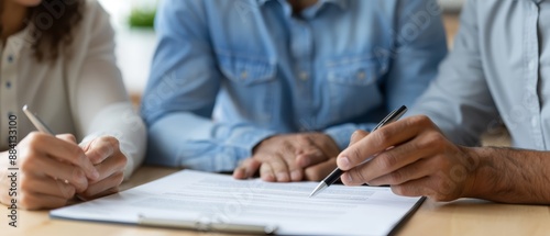  A cohesive group gathers around a table, each person holding a pen and ready to write on their individual sheets of paper