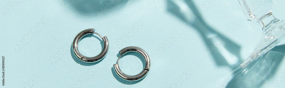 Creative composition with silver jewelry on blue background. Trendy accessories in minimalist style Creative composition with silver jewelry on blue background. Trendy accessories in minimalist style