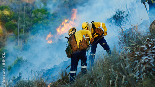 Smoke, teamwork and firefighter in bush for emergency, disaster management or damage control in forest. Mountain, flame and people with fire rescue, volunteer service or safety in nature conservation photo