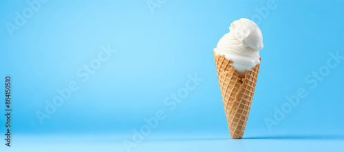 Single Scoop Vanilla Ice Cream Cone on Blue Background:  White Creamy Ice Cream in Waffle Cone on Vibrant Pastel Blue Backdrop - Minimalist Background Banner with Copy Space