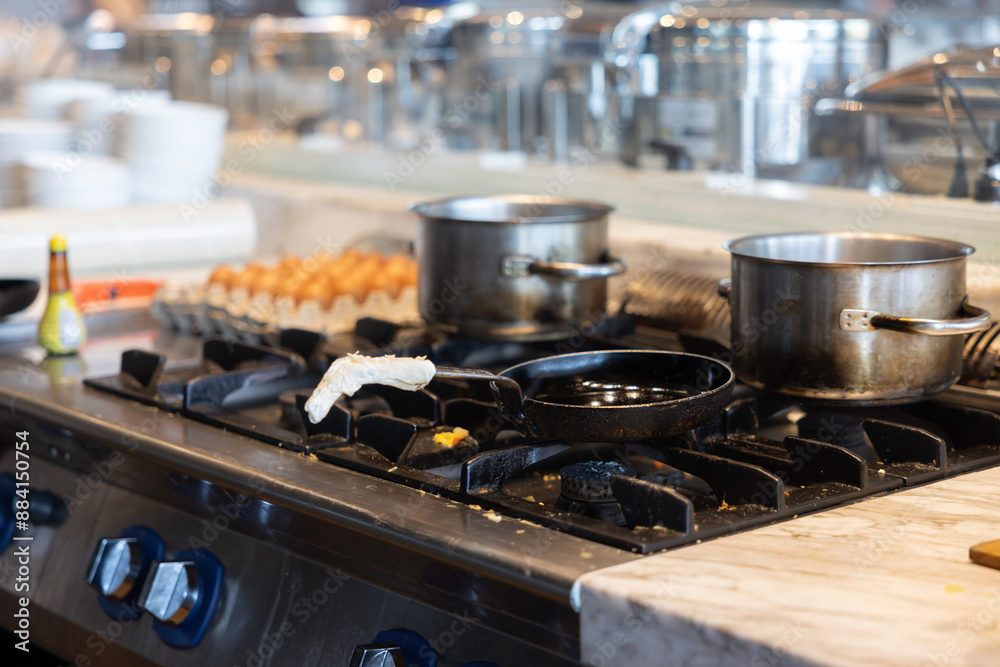 A stove top with two pots on it, one of which is black and the other is silver A stove top with two pots on it, one of which is black and the other is silver