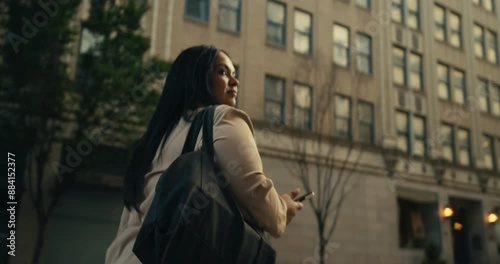 Young business woman walking around the city using her phone and laptop