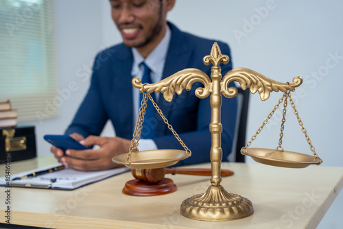 An Asian businessman in a formal suit works alone at a lawyer's desk, by golden scales, law books, leather bags, and a Lady Justice statue, emphasizing personal freedom and legal empowerment. photo