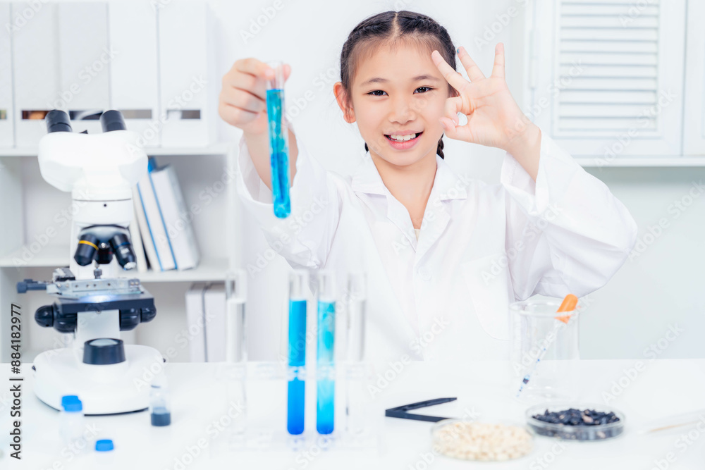 A young girl in a lab coat proudly showing a test tube with blue liquid, demonstrating success and joy in scientific experimentation in a bright laboratory setting.