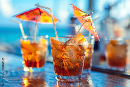 Cocktail with ice and umbrella on the background of the sea. Refreshing drink with ice and straw on the background of yachts. photo