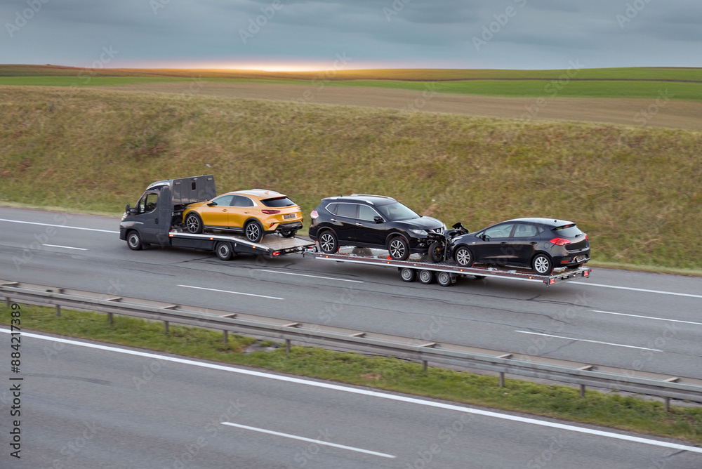 Fototapeta premium Flatbed Truck Transporting SUV Hatchbacks And Motorcycle