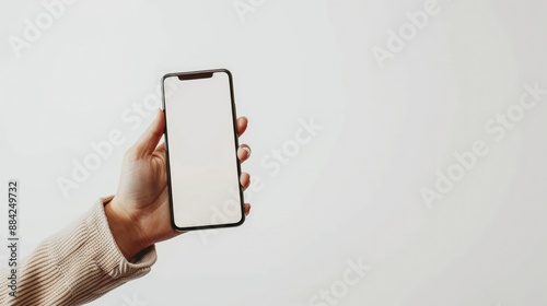 female hand with white sweater holding modern phone in vertical position with empty screen on white background. Mockup easy to edit