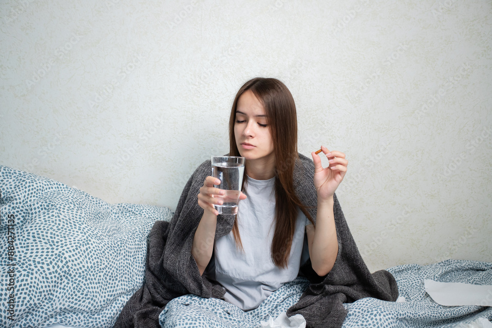 Sick teenager taking medication, dealing with a high temperature, resting at home. Sick teenager taking medication, dealing with a high temperature, resting at home.