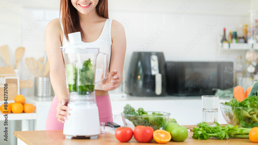Attractive sporty young woman making vegetable smoothie with blender in kitchen. Healthy lifestyle and dieting concept. Attractive sporty young woman making vegetable smoothie with blender in kitchen. Healthy lifestyle and dieting concept.