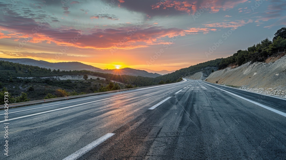 Fototapeta premium Panoramic sunrise view of an asphalt highway with natural mountain scenery, capturing the serene beauty of dawn.