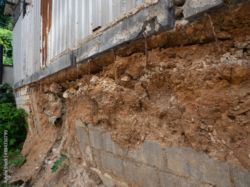 Broken wall with soil erosion from low standard construction.