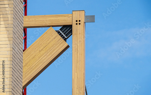 Laminated mass timber construction detail of intersecting horizontal and vertical and angled beam elements against a blue sky photo