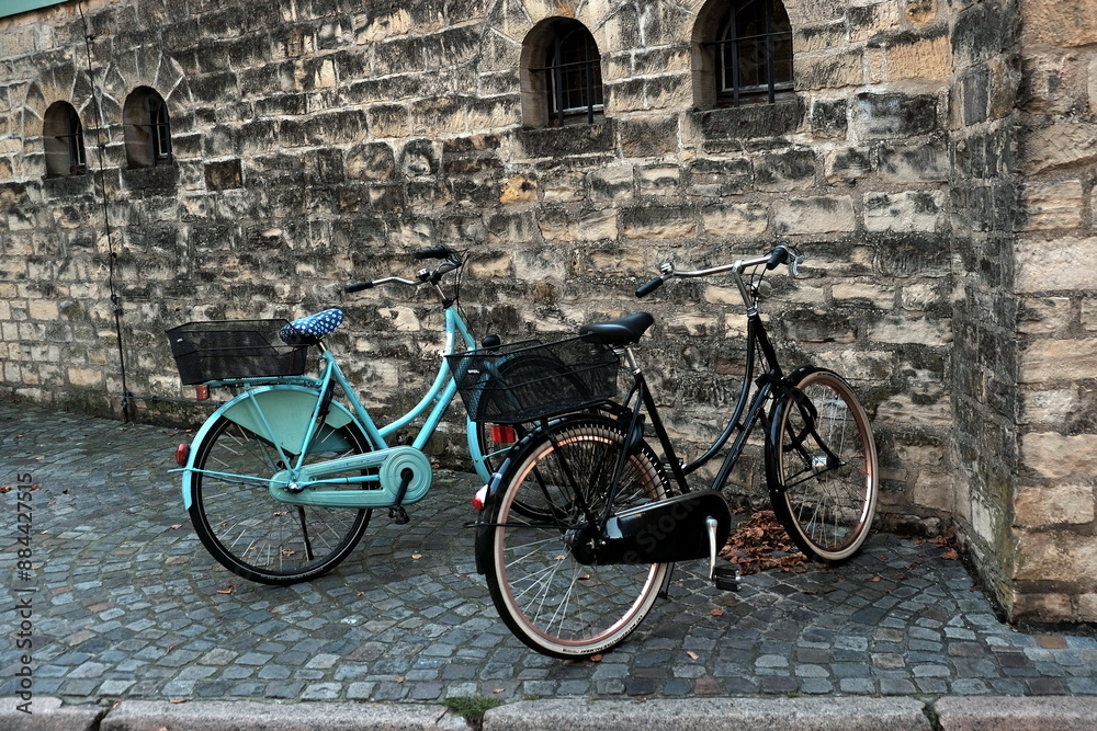 Geparkte Hollandräder mit Fahrradkorb am Sankt Paulus Dom mit altem Mauerwerk aus Naturstein und altem Kopfsteinpflaster am Domplatz in der Altstadt und City von Münster in Westfalen im Münsterland Geparkte Hollandräder mit Fahrradkorb am Sankt Paulus Dom mit altem Mauerwerk aus Naturstein und altem Kopfsteinpflaster am Domplatz in der Altstadt und City von Münster in Westfalen im Münsterland