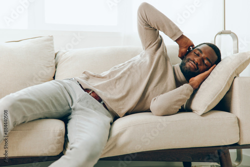 Relaxed African American Man Sitting on Sofa, Smiling and Enjoying a Weekend at Home
