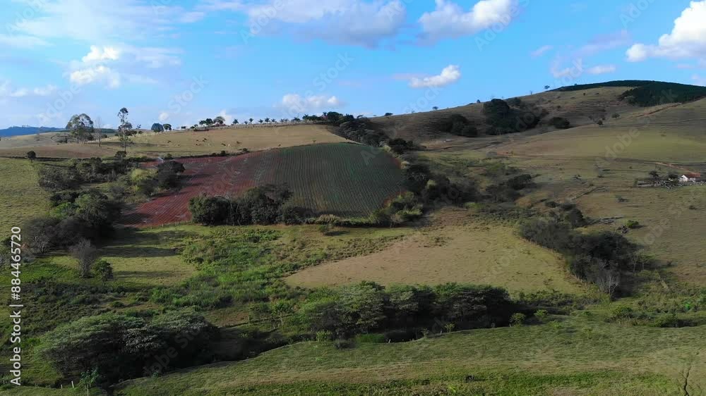 The image shows a rural landscape of a countryside with a field in the foreground and a hill in the background.