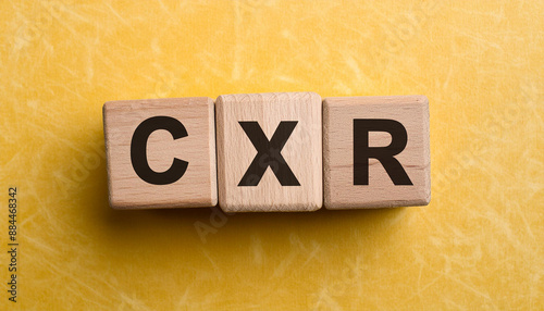 Wooden cubes with abbreviation CXR yellow background. Chest X-Ray. Medical concept. Flat lay photo