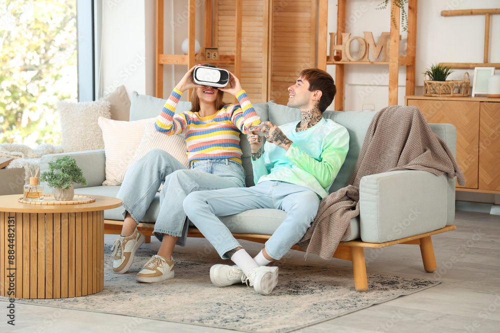 Obraz premium Young man with mobile phone and his girlfriend using VR glasses at home