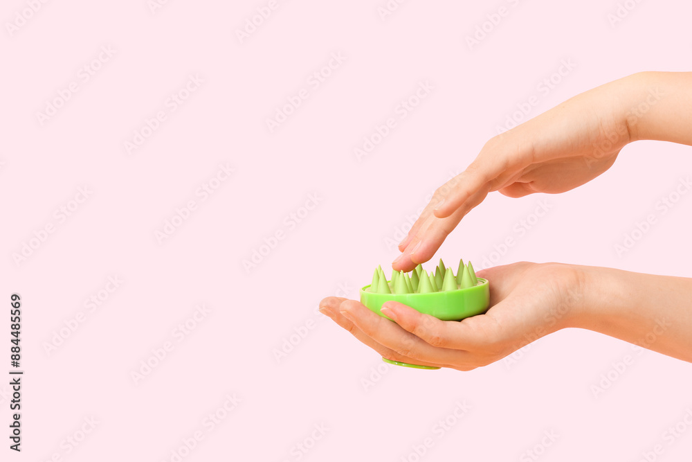 Female hands with silicone head massage brush on pink background Female hands with silicone head massage brush on pink background