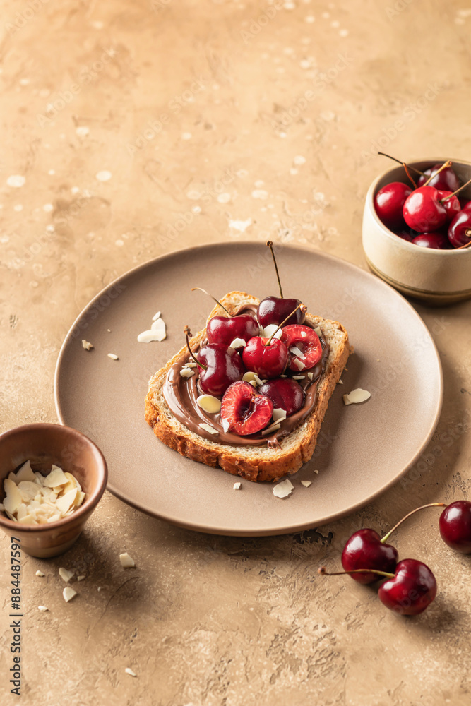 Breakfast toast with chocolate paste, sweet cherry and almond petals on beige textured background, text space Breakfast toast with chocolate paste, sweet cherry and almond petals on beige textured background, text space