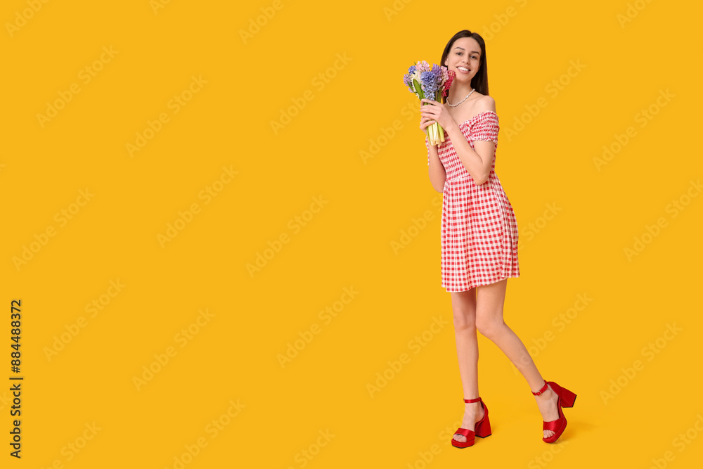 Fototapeta premium Happy smiling young woman with hyacinth flowers on yellow background