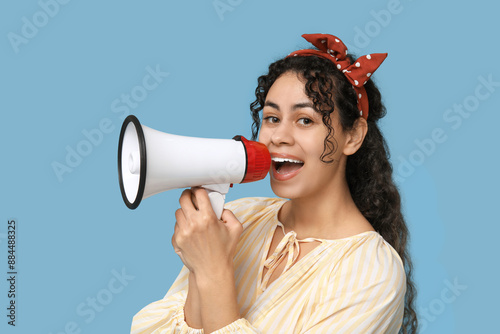 Young African-American woman with megaphone on blue background