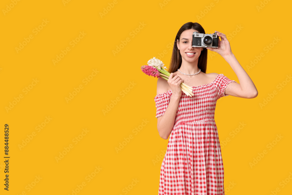 Obraz premium Happy smiling young woman with hyacinth flowers and camera on yellow background