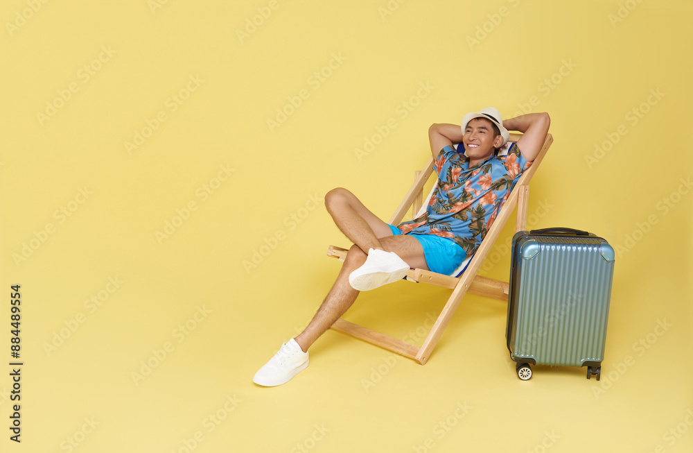 Young asian travel man wear summer clothes sit in deckchair put hands behind head relaxing isolated on yellow background. Young asian travel man wear summer clothes sit in deckchair put hands behind head relaxing isolated on yellow background.