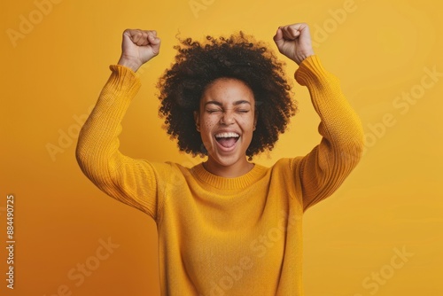 Feeling Ecstatic, A Happy Young Woman with Raised Fists on a solid color Background photo