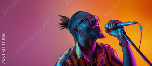 african american musician singing on gradient colorful studio background in neon light. Concept of music, hobby, festival. Joyful party host, stand upper. Colorful portrait of artist