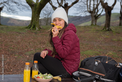 mountaineer woman eating banana in the autumn forest