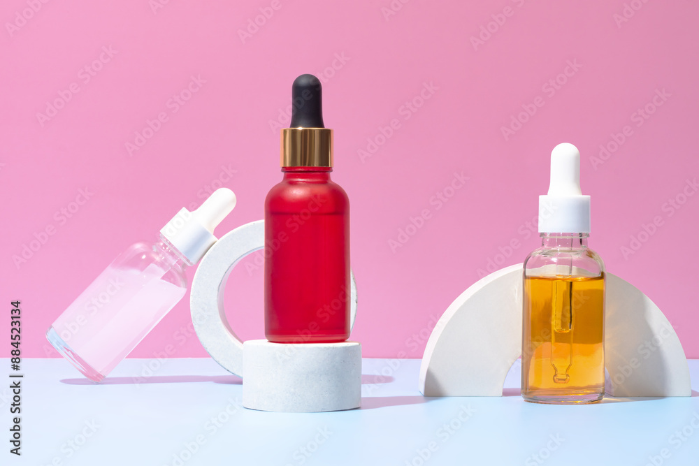 Vibrant dropper bottles on modern podium set against a pink backdrop