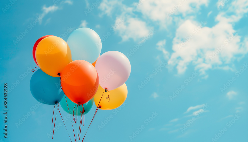 Colorful helium balloons float gracefully in the sky. Surrounded by fluffy white clouds against a vibrant blue backdrop with copyspace Colorful helium balloons float gracefully in the sky. Surrounded by fluffy white clouds against a vibrant blue backdrop with copyspace