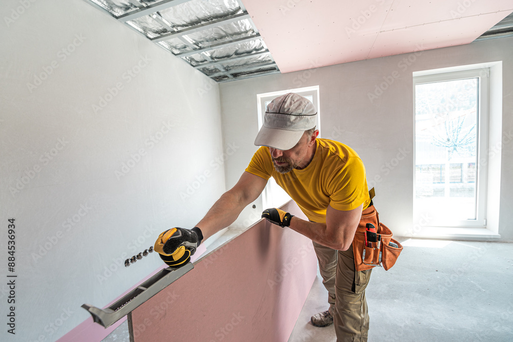 The worker make a plasterboard ceiling. He doing adjust the edge of the ...