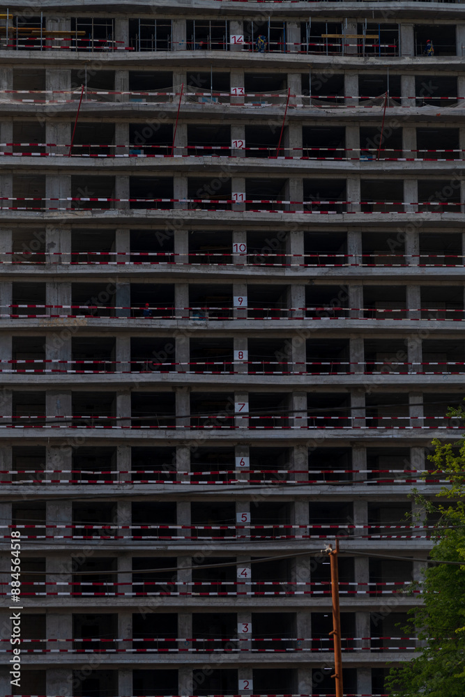 Close-up side view of dark concrete wall of modern skyscraper building under construction. Copy space. Abstract construction background. Housing development theme. Close-up side view of dark concrete wall of modern skyscraper building under construction. Copy space. Abstract construction background. Housing development theme.