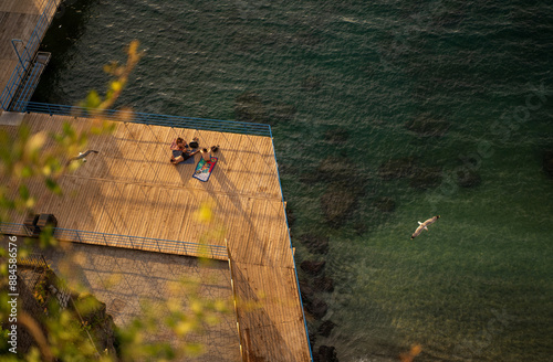 Obraz na płótnie A beautiful view of wooden platform on a beach with people relaxing and birds flying across on a marina beach of Sorrento, Italy w salonie