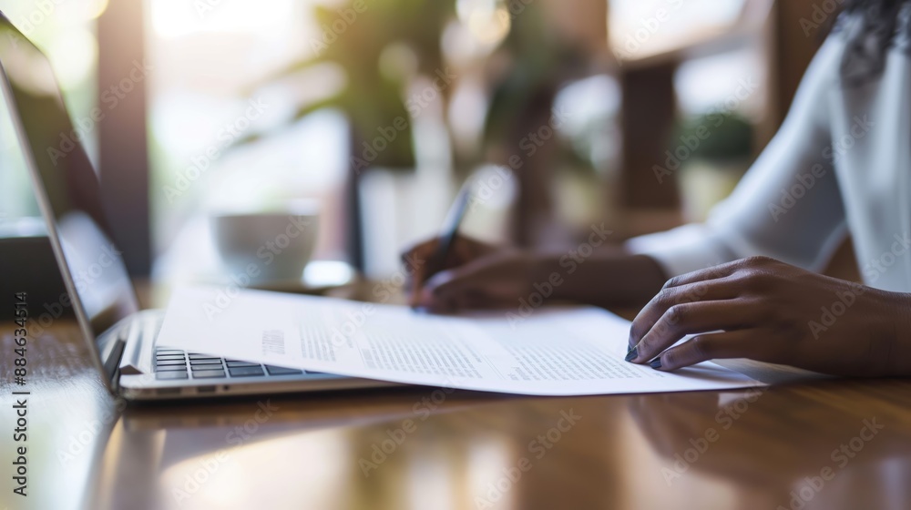 Hands Writing on Document at Brightly Lit Wooden Desk with Laptop Hands Writing on Document at Brightly Lit Wooden Desk with Laptop