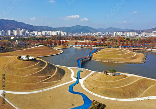 Pungdeok-dong, Suncheon-si, Jeollanam-do, South Korea - November 23, 2022: Aerial and autumnal view of blue deck trail with pond and hill at Suncheon Bay National Garden
 photo