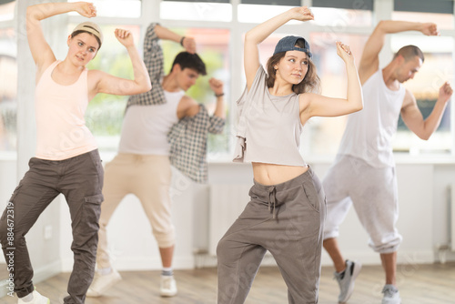 Girl makes movements and teaches group of hip hop fans to move beautifully and confidently to music, to control their bodies. Young boys and girl repeat after teacher