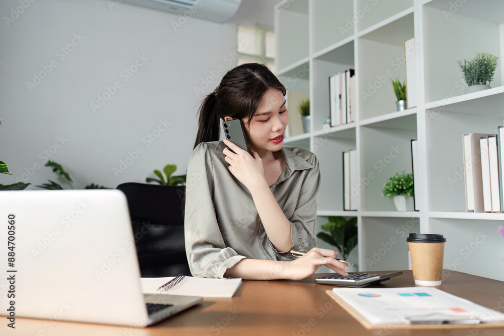Young Professional Woman Working from Home Office with Laptop, Smartphone, and Calculator Young Professional Woman Working from Home Office with Laptop, Smartphone, and Calculator